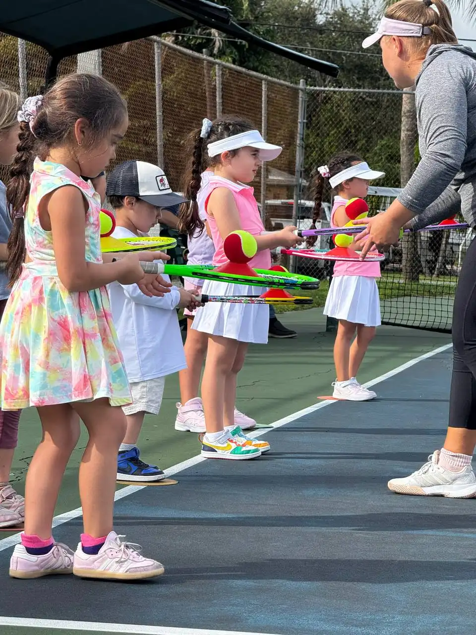 Young players holding rackets and balls in a line