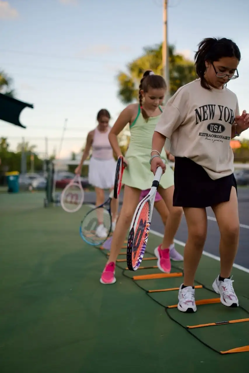 Kids with rackets lined up on a green court