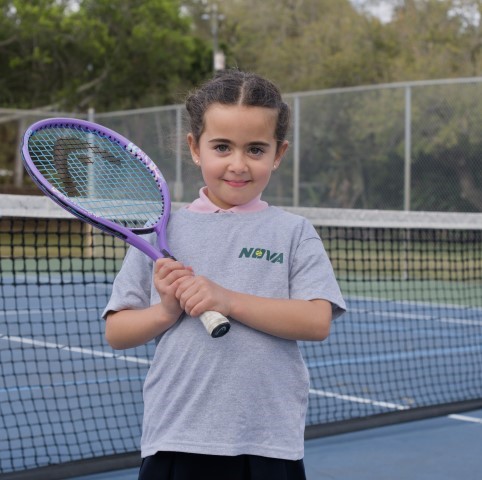 Girl with a purple racket standing at the net
