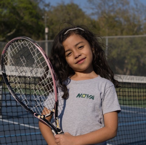 Girl in a NOVA T-shirt holding her racket at the net