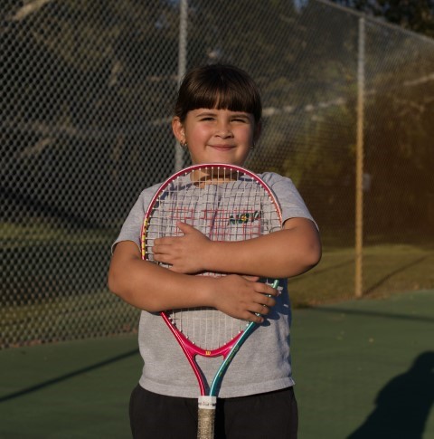 Girl hugging a pink racket in the evening sun