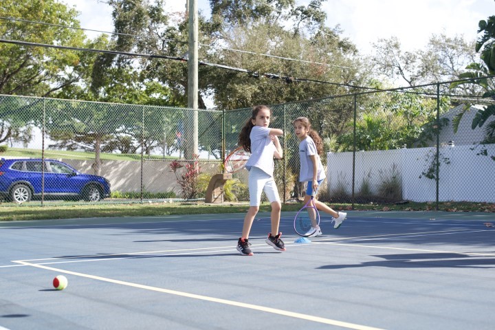 Two girls rallying on a hard court