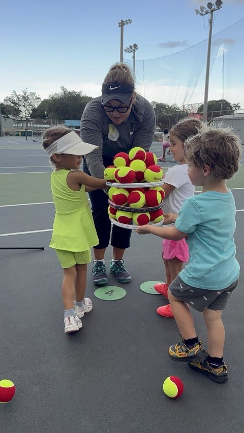 Coach holding a bundle of red and orange balls for small children