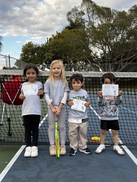 Four young players with their certificates at the net